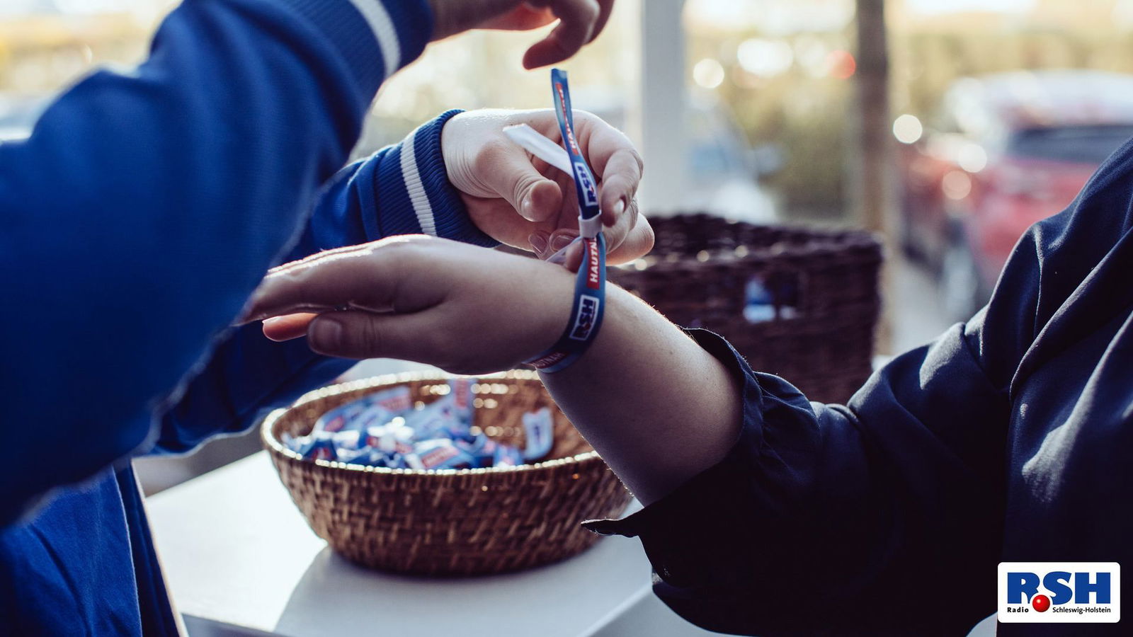 Mann macht einer Frau ein RSH Festivalband um den Arm