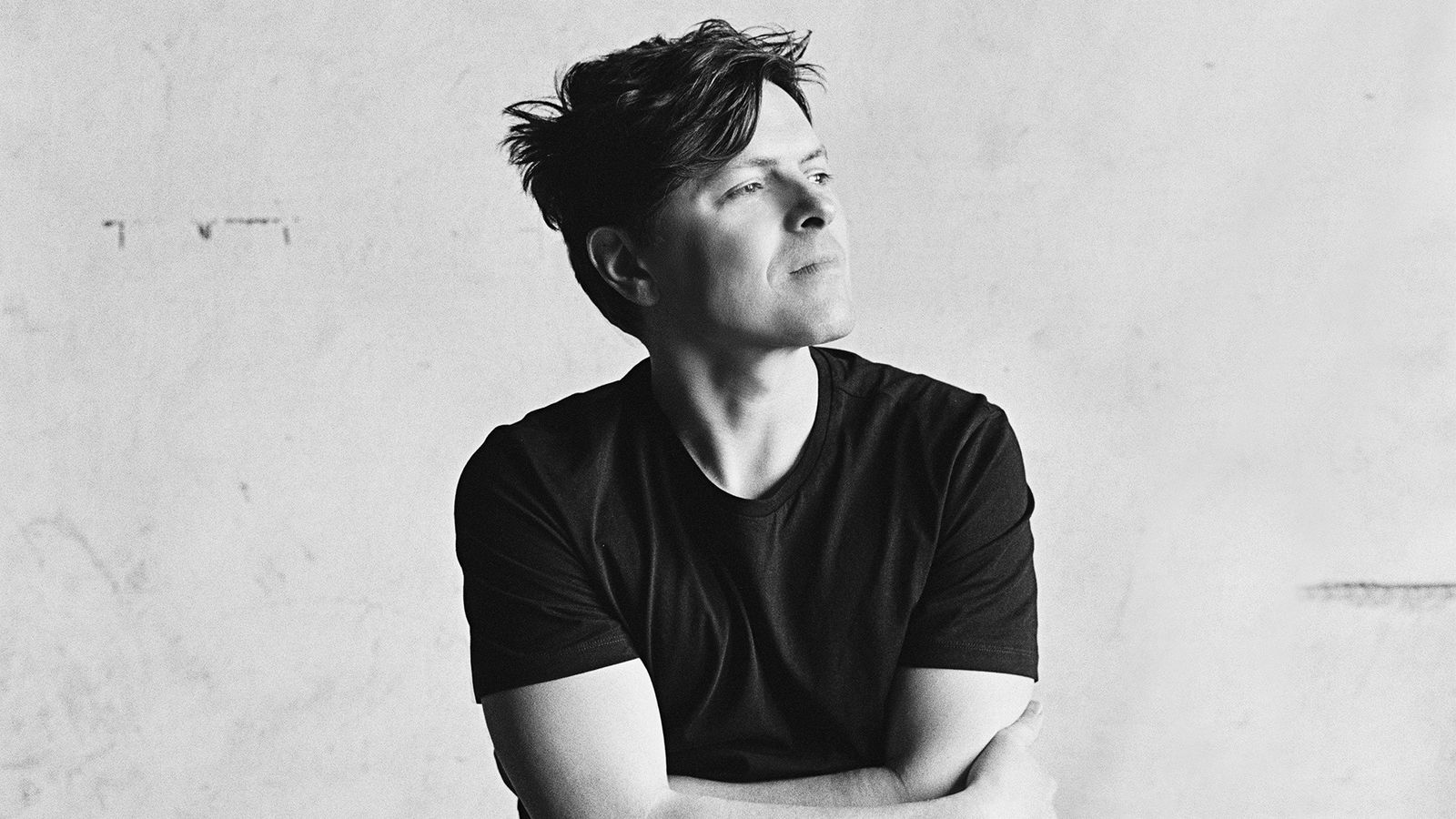 Michael Patrick Kelly verschränkt die Arme und grinst.