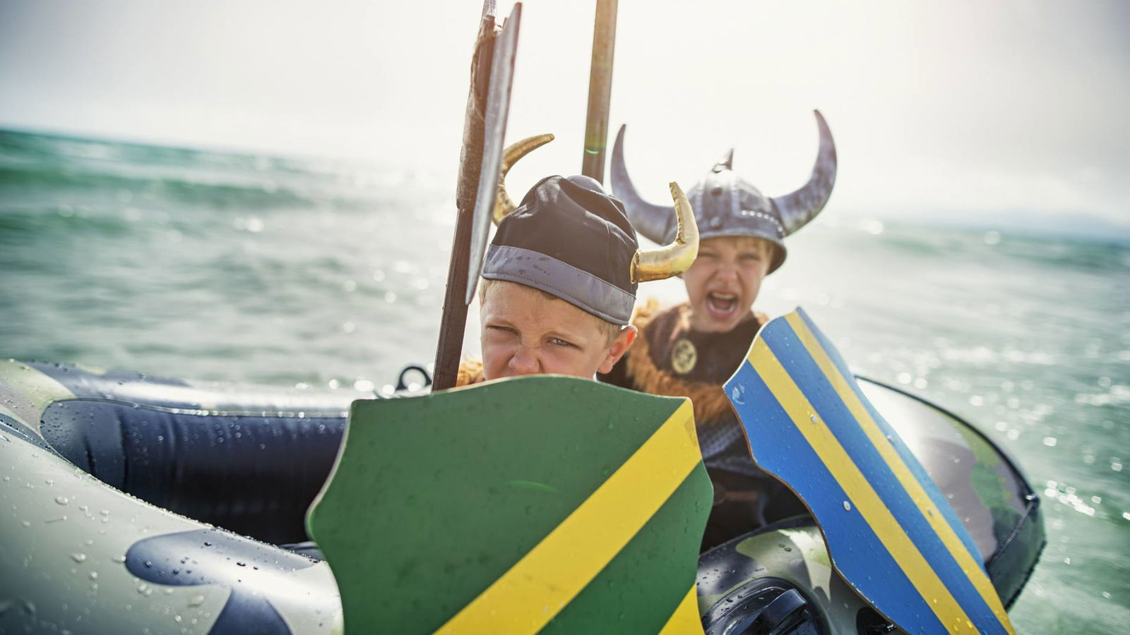 Zwei Kinder sitzen als Wikinger verkleidet in einem Schlauchboot.