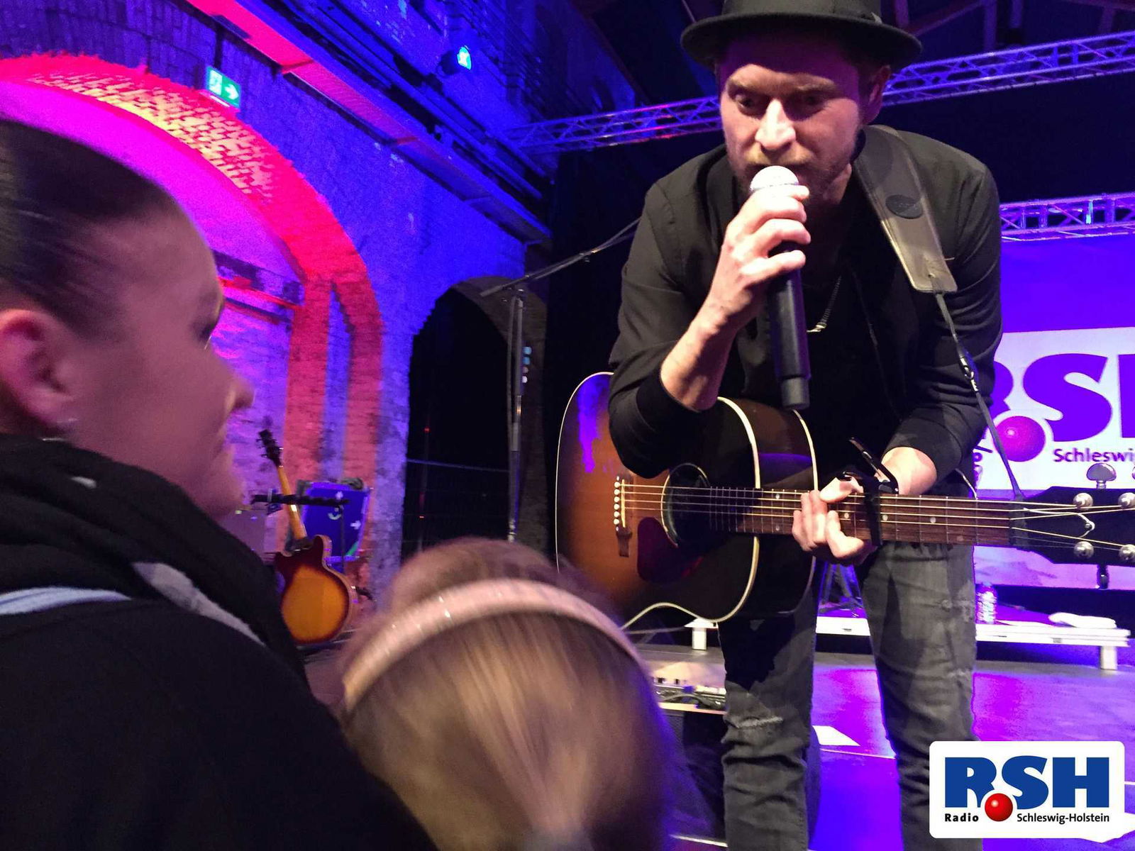 Johannes Oerding spricht auf der Bühne ins Mikrofon.