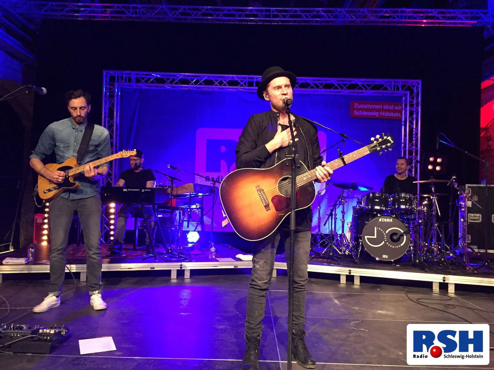 Johannes Oerding steht auf der Bühne und spricht mit dem Publikum.