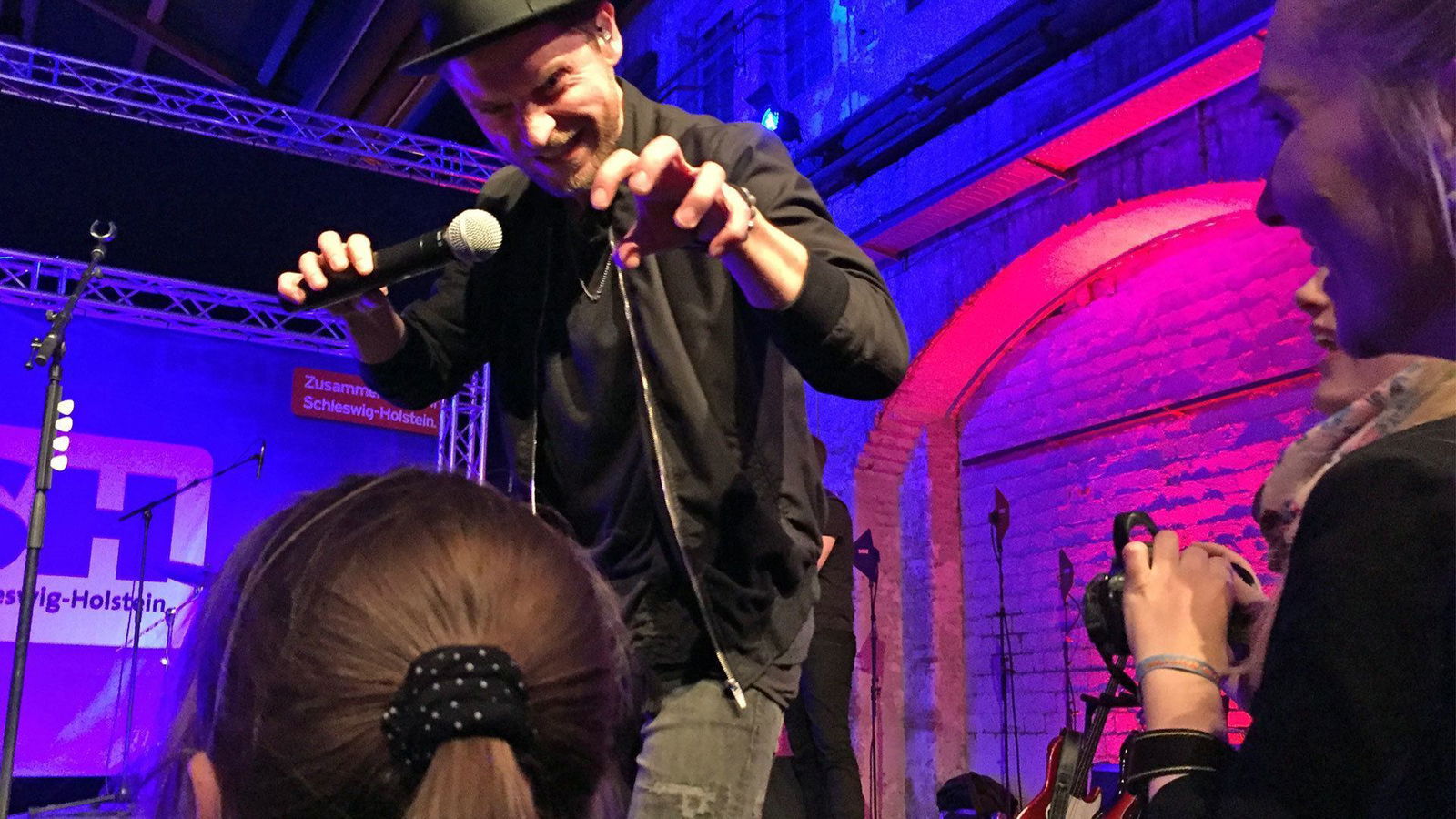 Johannes Oerding steht auf der Bühne und macht mit seinen Händen eine Kralle über das Publikum.