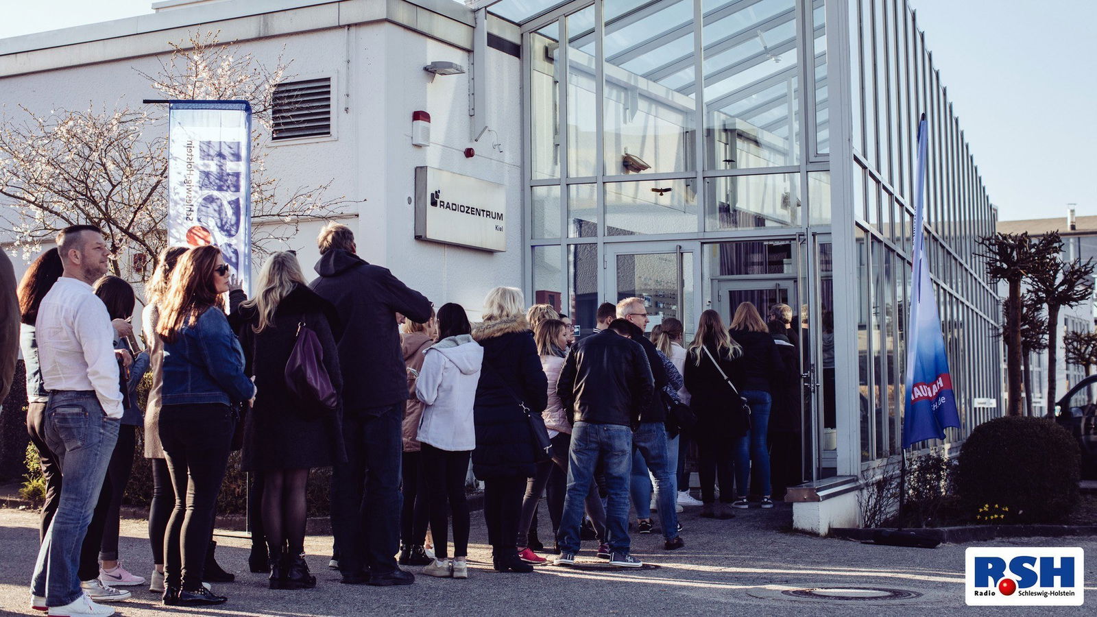 Eine Menschenschlange steht vor dem Funkhaus in Kiel.