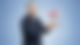 Marco Chwalek steht vor einem blauen Hintergrund, schaut in die Kamera und wirft ein rotes Schild in die Luft auf dem in weiß on air steht.