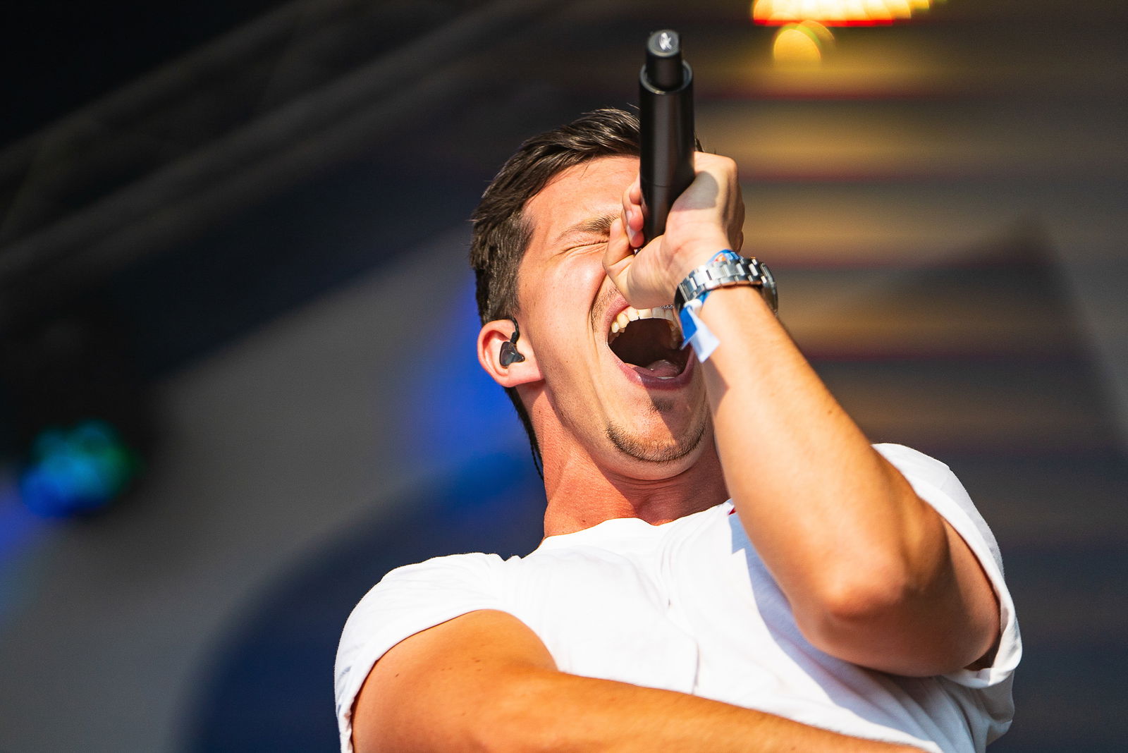 Ein Sänger steht der Kamera zugewandt. Er singt in ein Mikrofon und hat dabei die Augen geschlossen. 