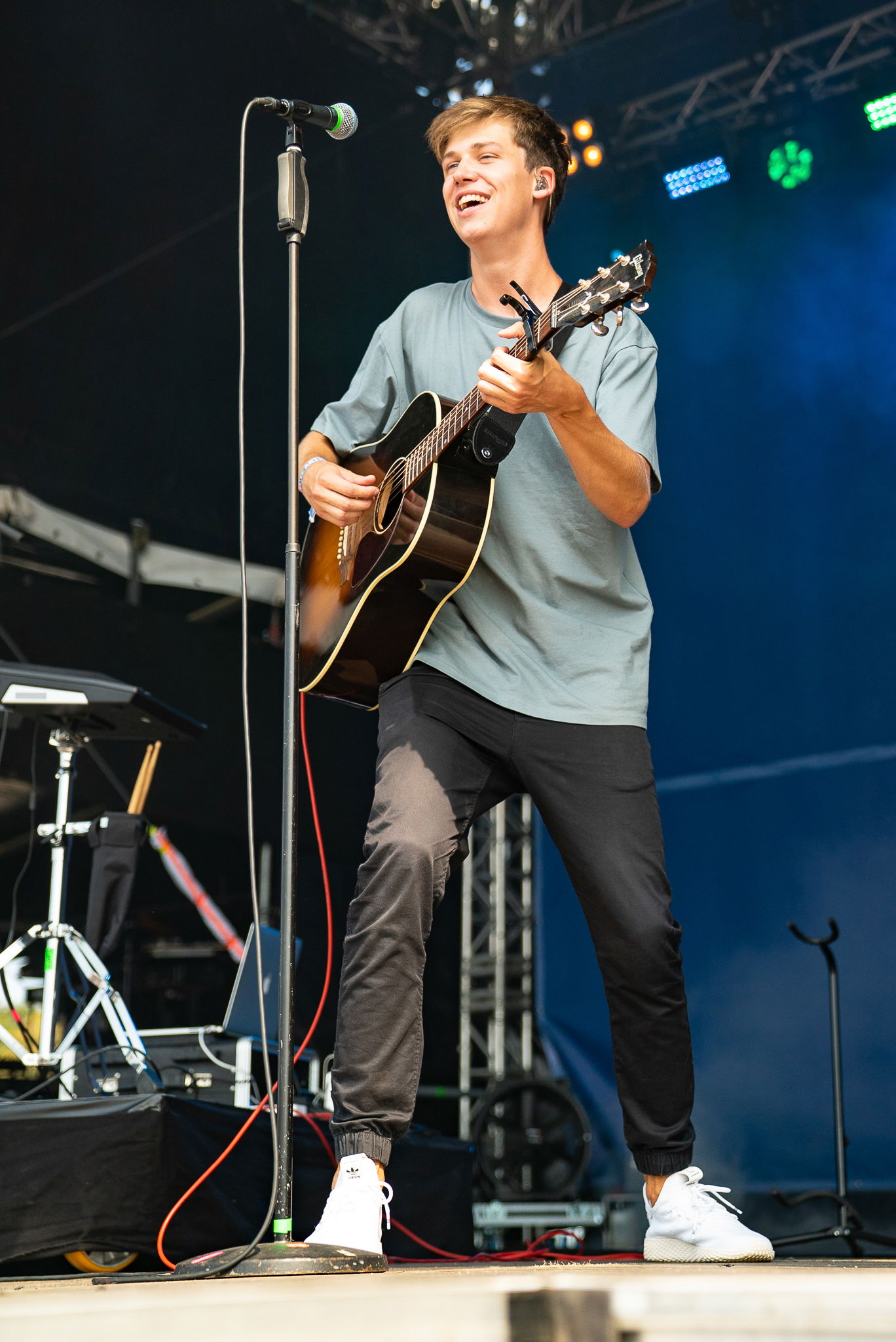 Ein junger Mann steht auf einer Bühne und spielt Gitarre.