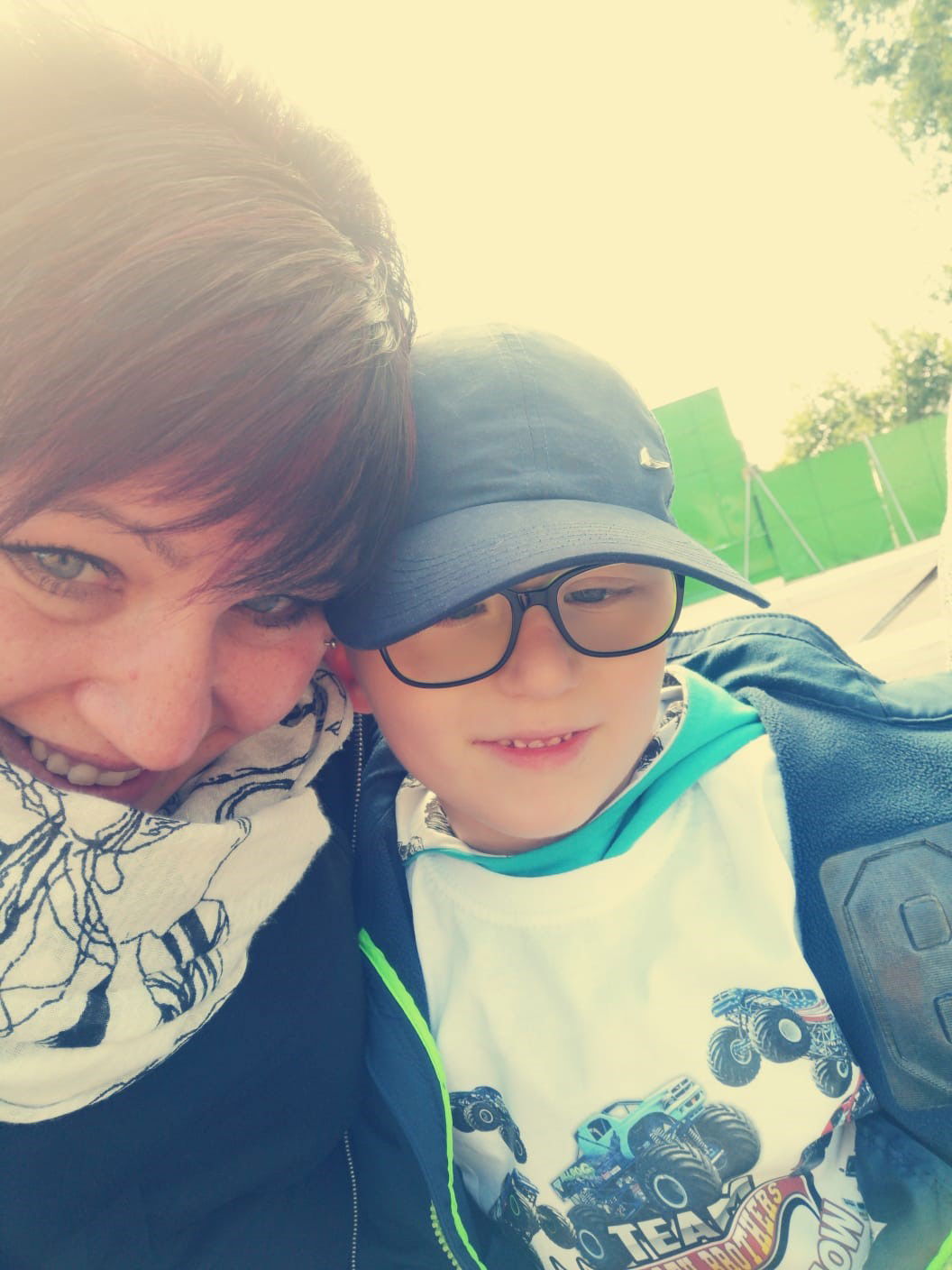 Eine Frau und ein kleiner Junge mit Brille und  Cappy stehen nah nebeneinander und gucken in die Kamera.