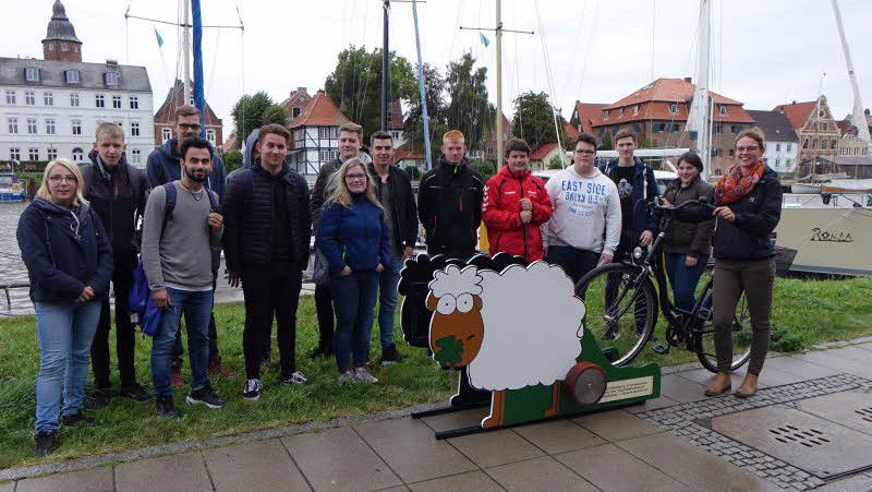 Menschen stehen vor einer Fahrradwaschanlage, die wie ein Schaf aussieht.