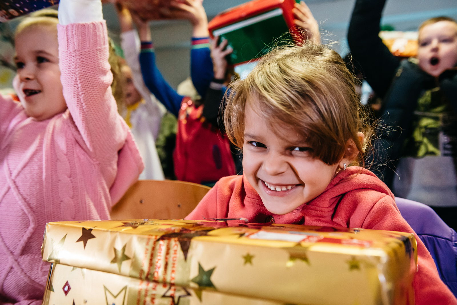 Ein Mädchen hält ein goldfarbenes Paket in der Hand und freut sich über das Geschenk