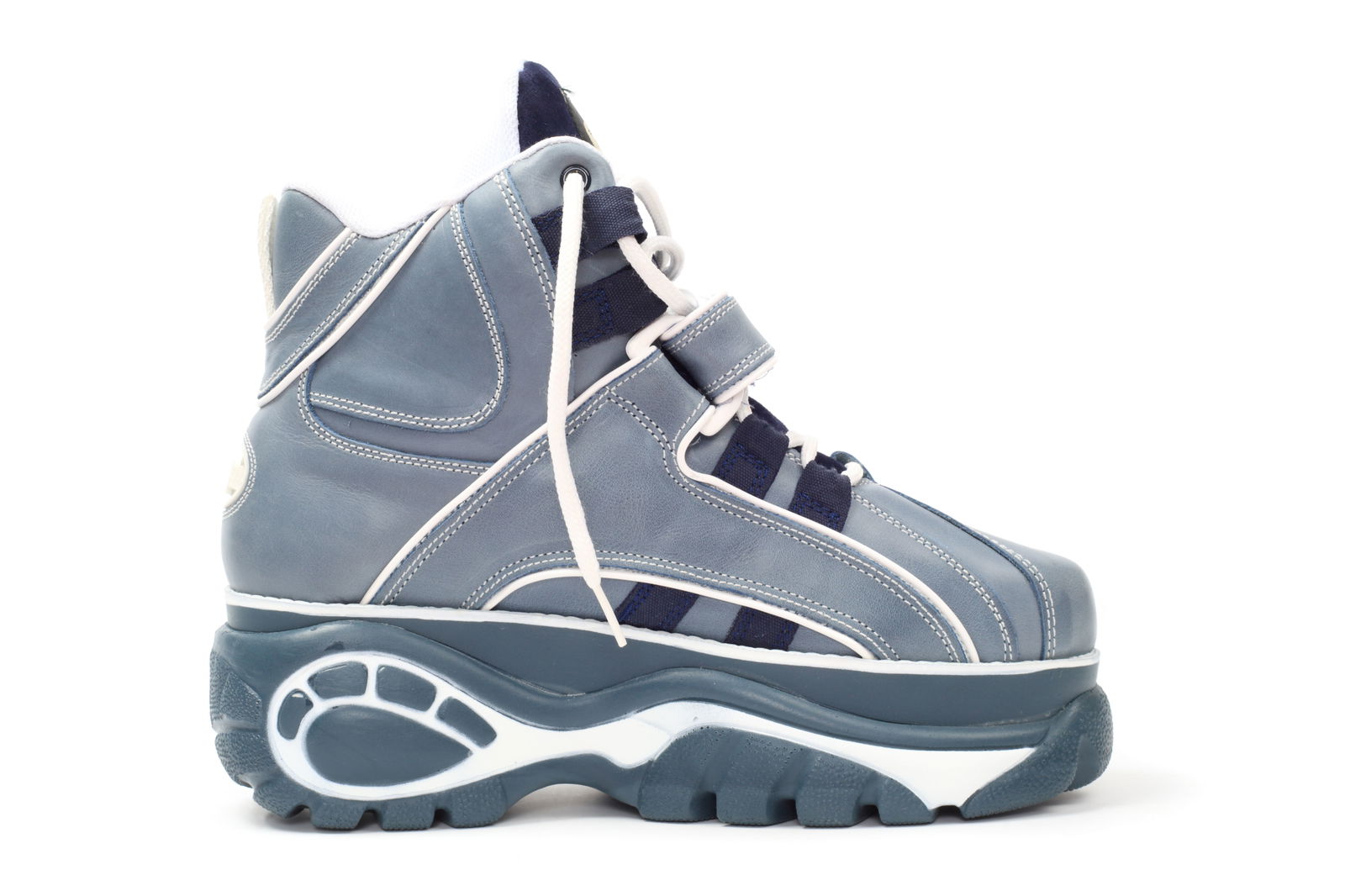 Ein Schuh mit Plateausohle steht vor einer Wand.