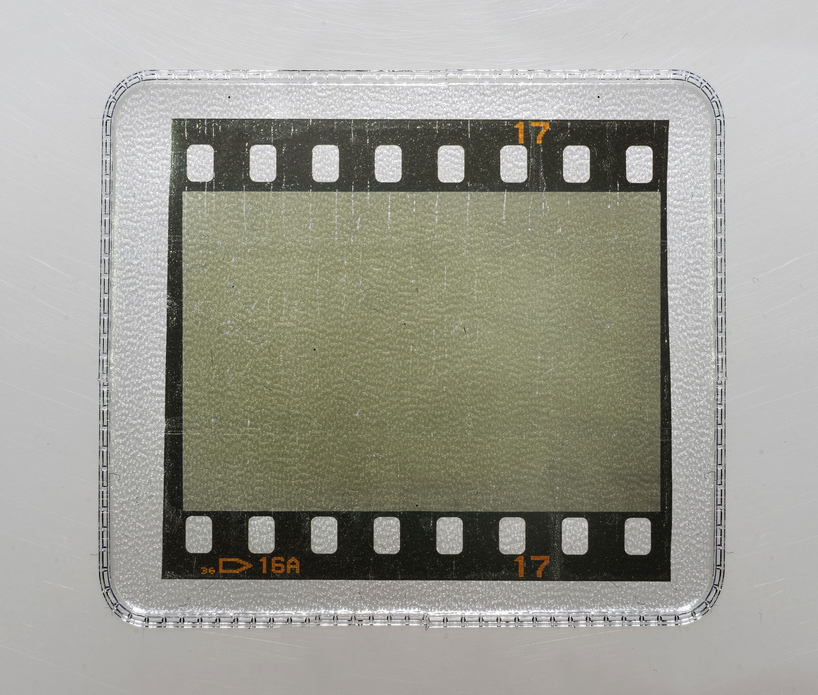 Ein einzelnes Dia liegt eingeschweißt in Plastik auf einem Untergrund. 