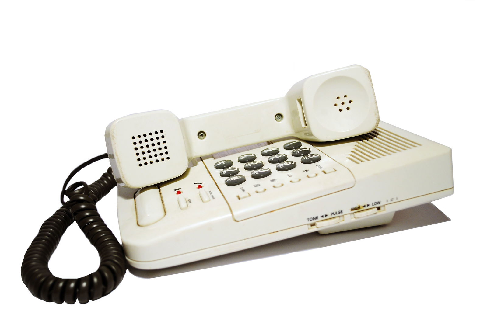 Auf einem Untergrund steht ein altes Kabeltelefon. Der Hörer ist auf das Telefon gelegt. Die Muscheln zeigen zur Kamera. 