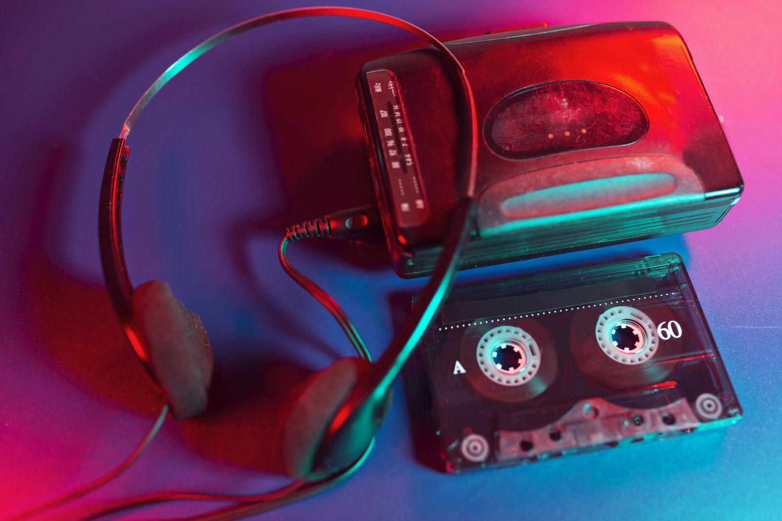Unter einem portablen Kassettenspieler liegt eine Kassette. Links daneben und zur Hälfte auf dem Gerät liegt ein Kopfhörer.