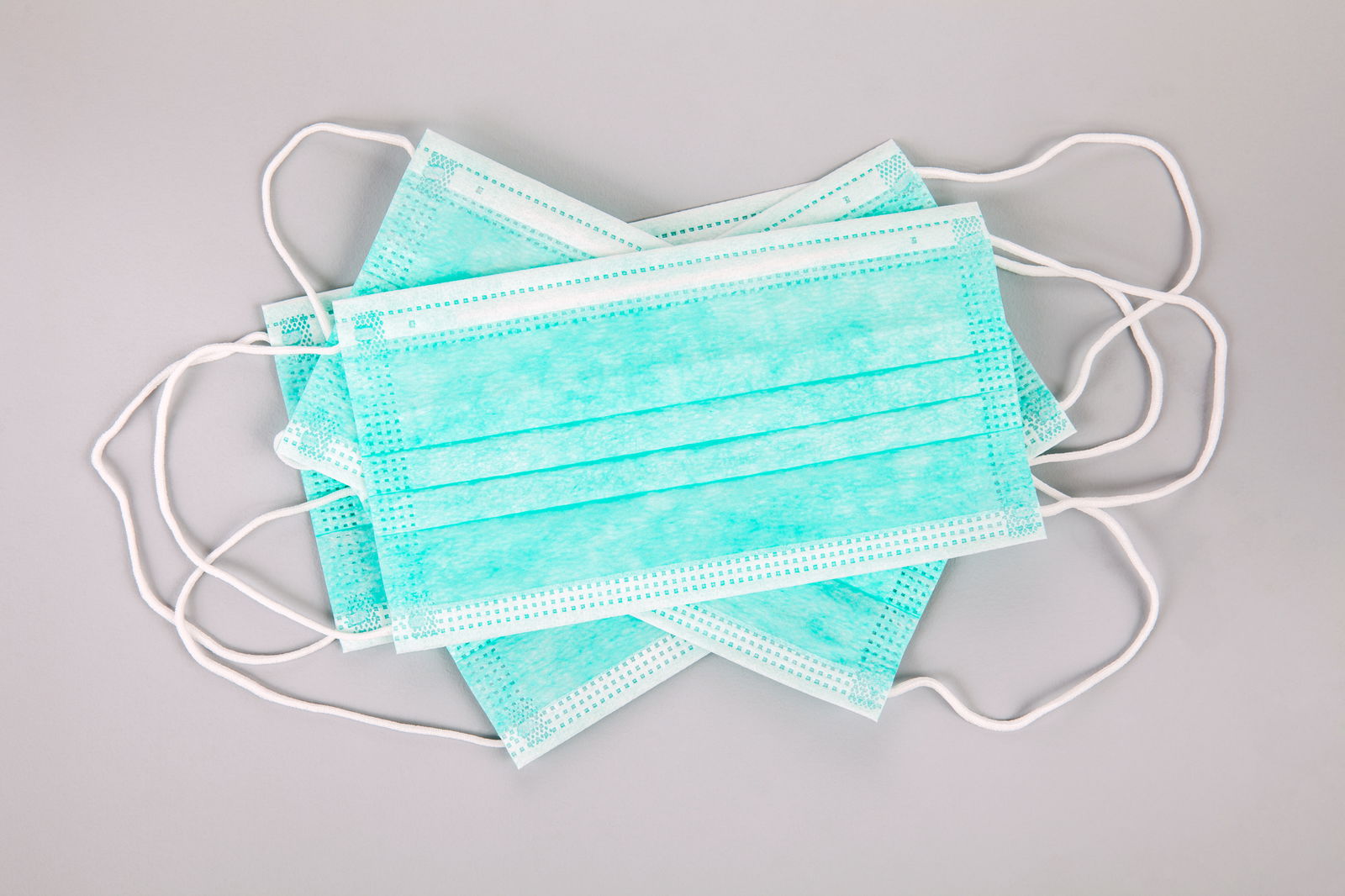 Auf einer hellen Unterlage liegen mehrere medizinische Mundschutze aufeinander. 
