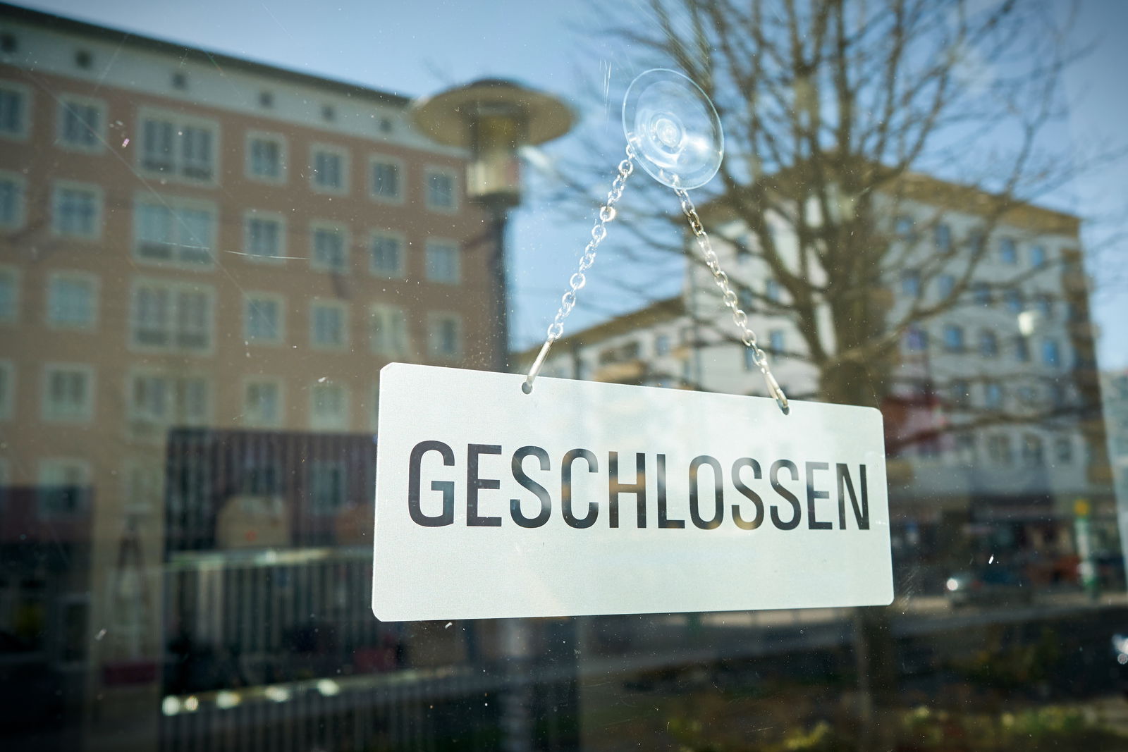 An einer Fensterscheibe ist ein Saugnapf befestigt. An dem ist an einer Eisenkette ein Schild mit der Aufschrift geschlossen aufgehangen.