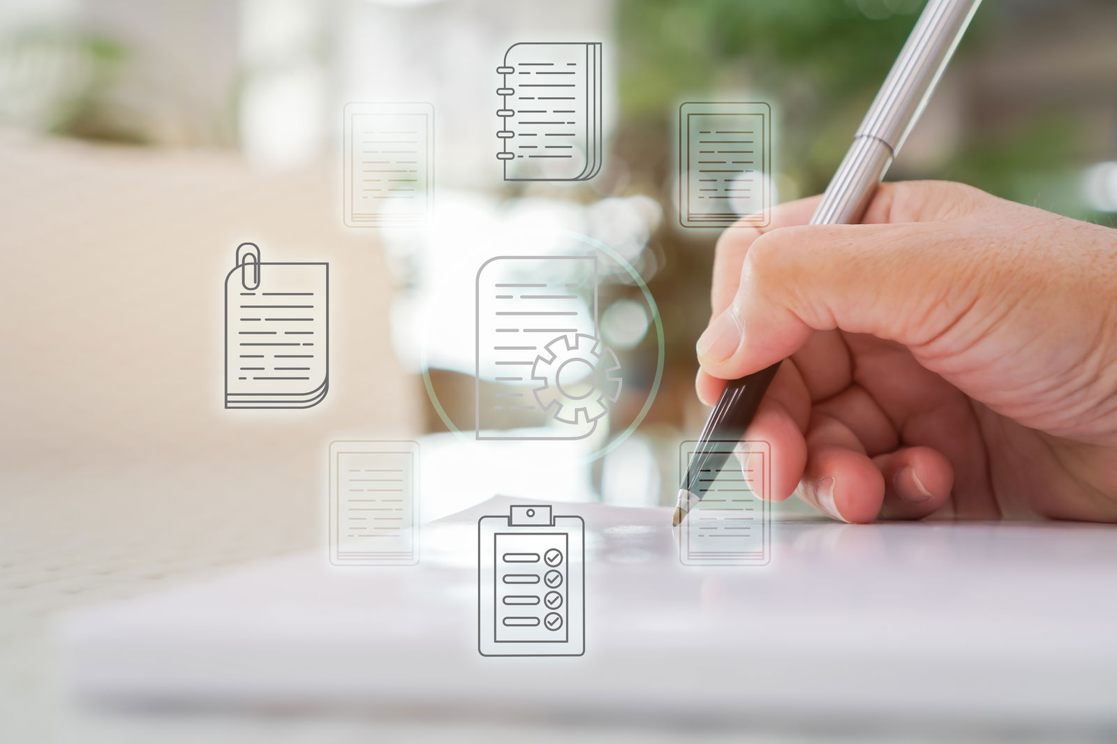 Eine Hand schreibt mit einem Kugelschreiber auf einem Blatt Papier. Im Vordergrund sind transparente Icons von Bürounterlagen angeordnet.