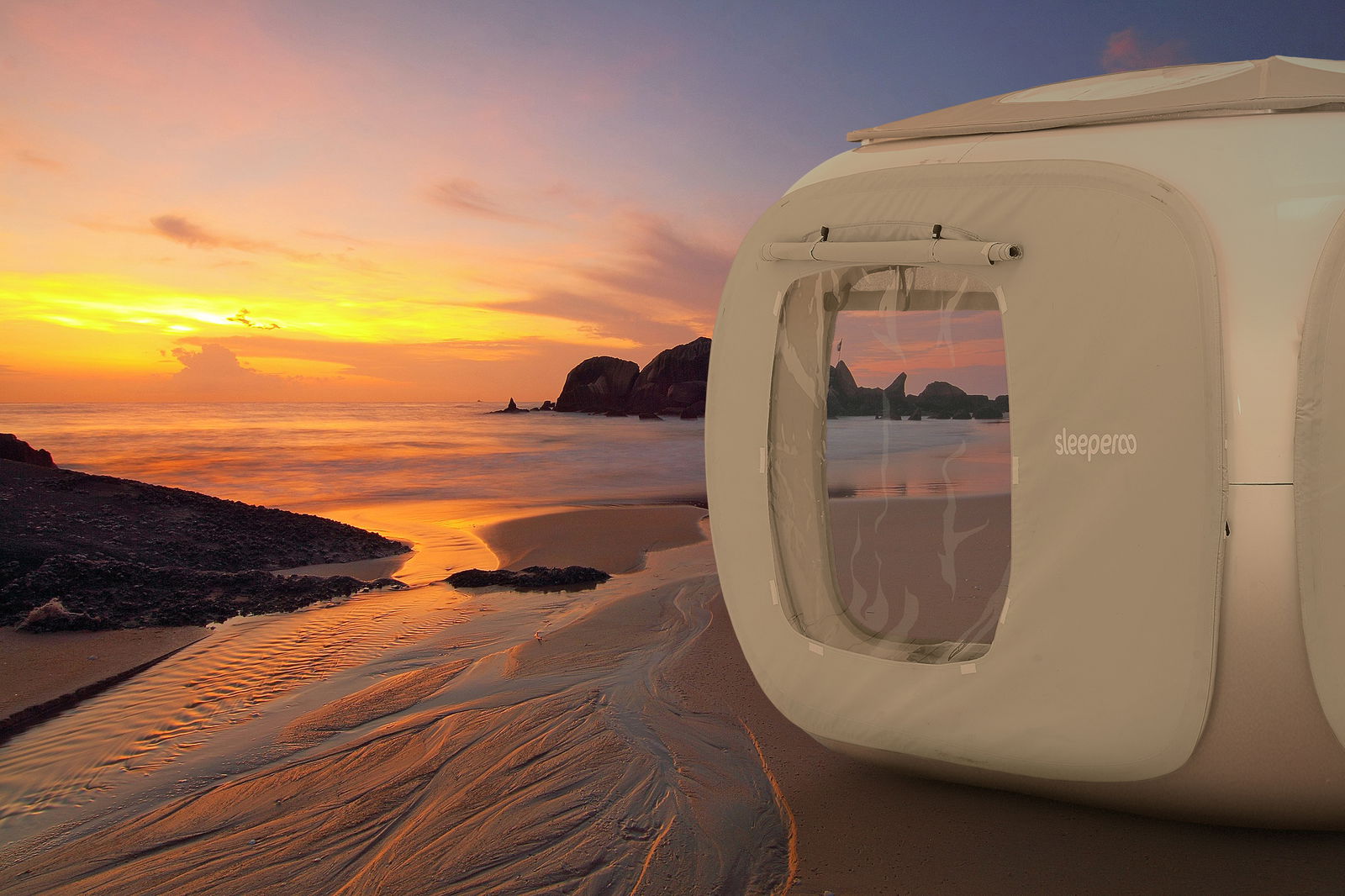 Ein weißer, großer Zelt-Würfel steht an einem Strand bei Sonnenuntergang.