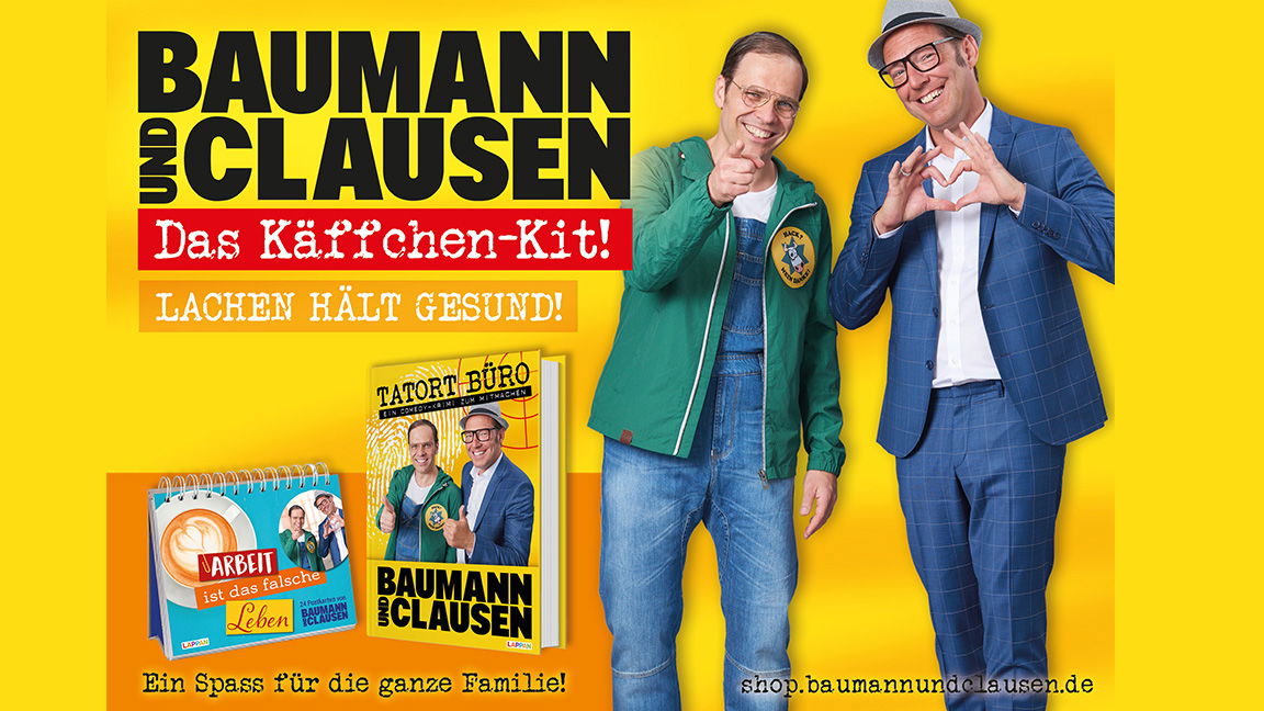 Zwei Männer stehen auf der rechten Seite vor einem gelben Hintergrund der Kamera zugewandt. Der linke von beiden zeigt in die Kamera, der rechte formt mit den Händen ein Herz.