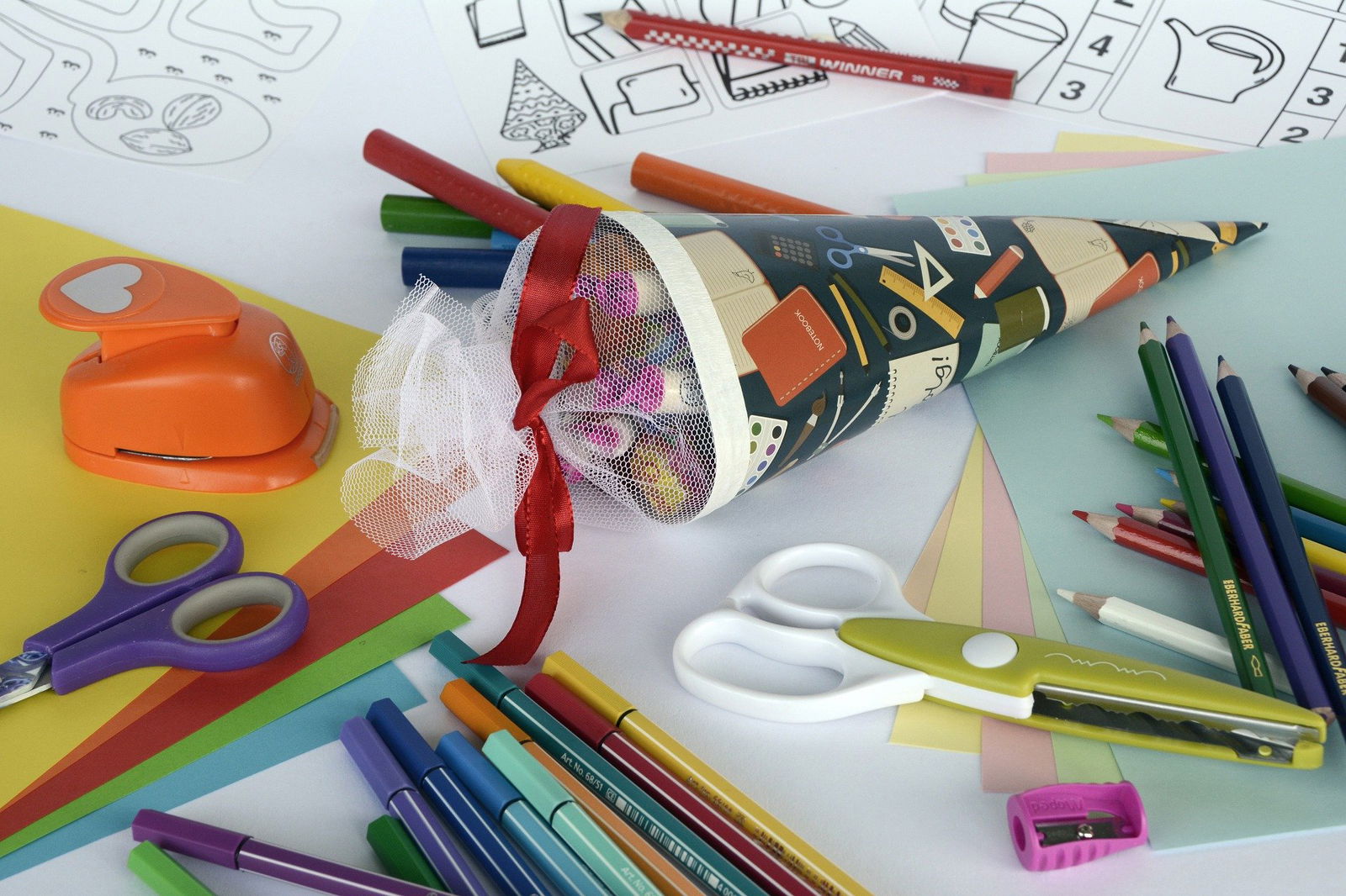 Eine vollgepackte Schultüte liegt auf einem Tisch mit verschiedenen Bastel-Utensilien.