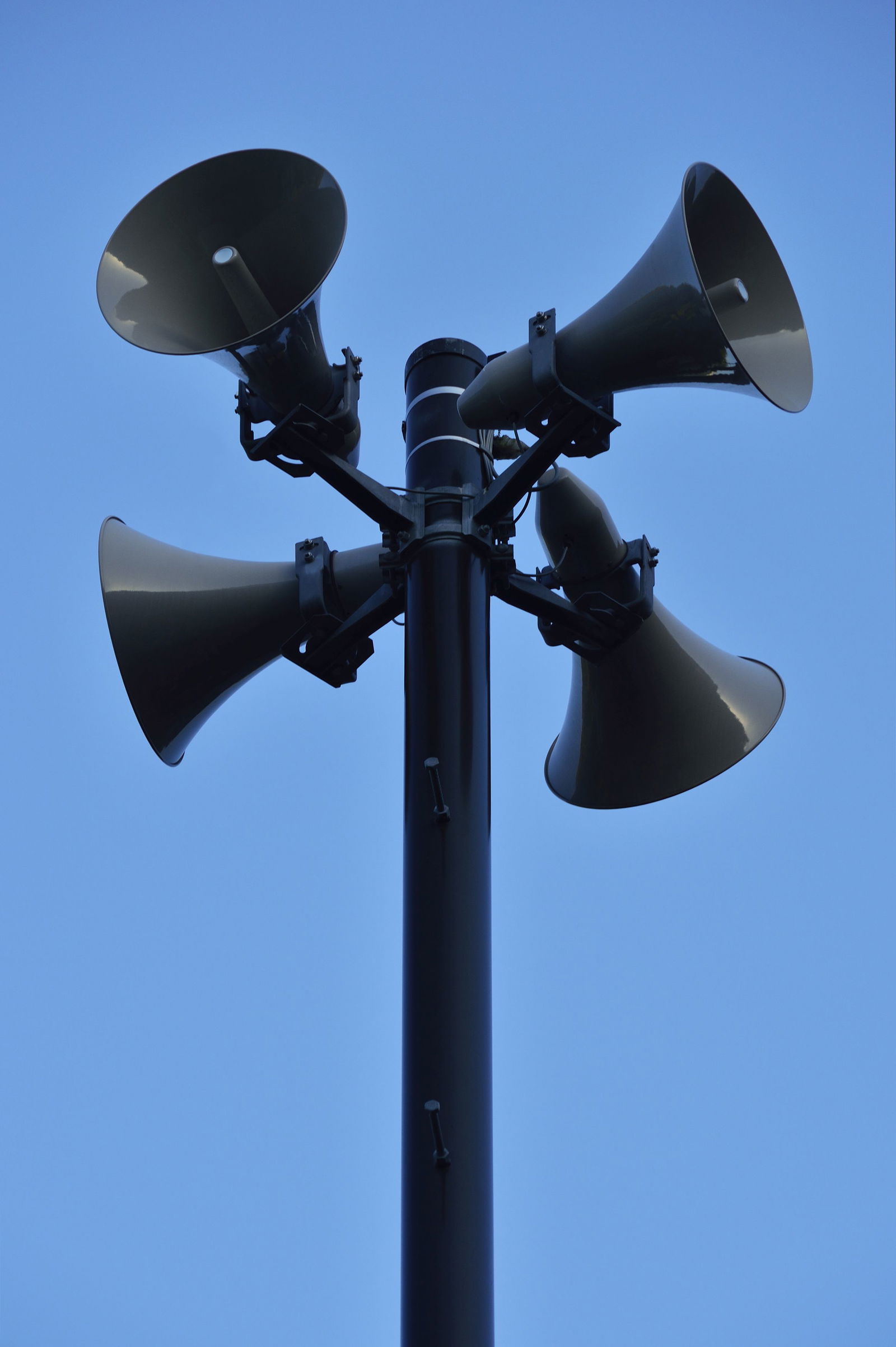 Vier Sirenen hängen im Kreis angeordnet an einem Mast.