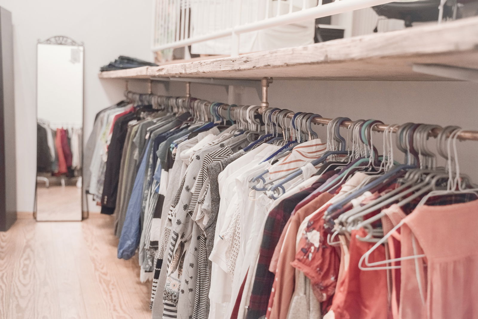 Auf einer langen Kleiderstange hängen an Bügeln viele verschiedene Klamotten.