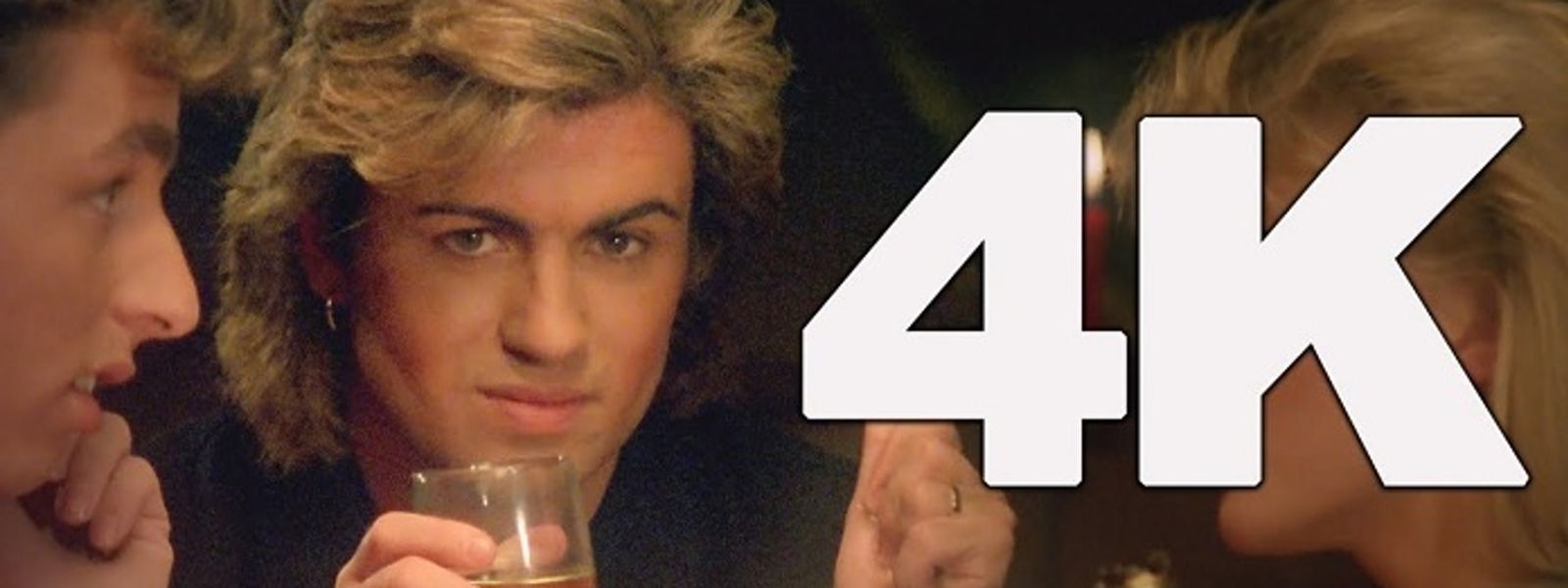 Ein Mann mit Weinglas schaut in die Kamera. Daneben steht groß 4K.