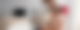 Eine Frau sitzt in einem Wohnzimmer vor einem Laptop und hat ein kleines Mädchen auf den Schultern sitzen, das mit ihr gemeinsam auf den Laptop schaut.