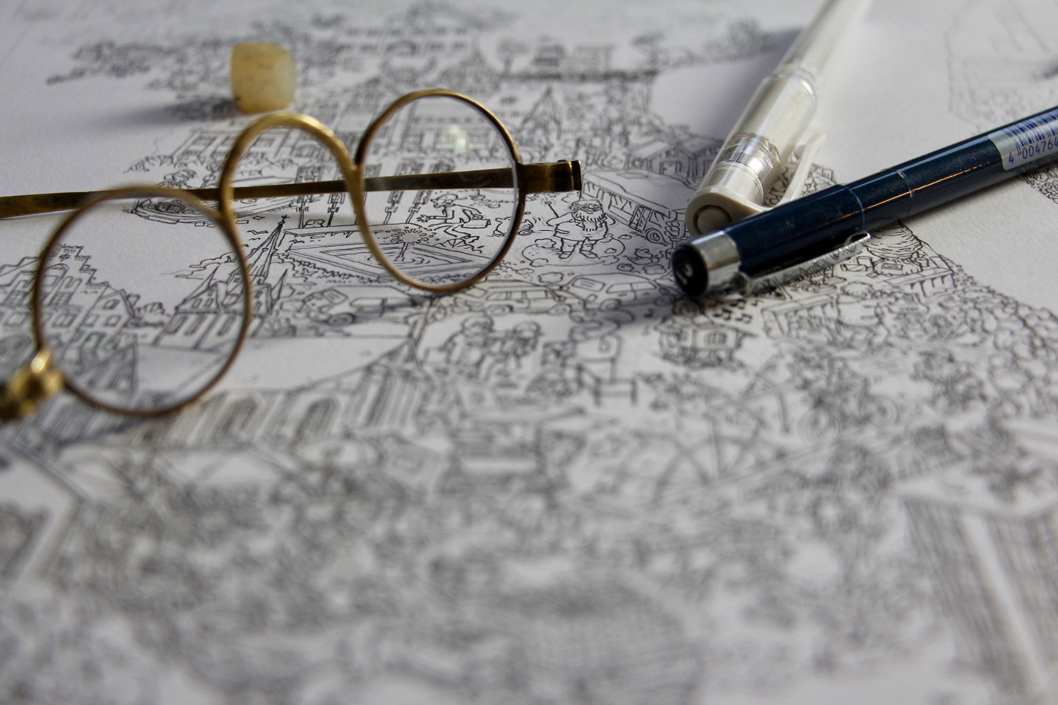 Auf einem schwarz-weißen Wimmelbild liegen eine runde goldene Brille, zwei Stifte und ein Radiergummi.