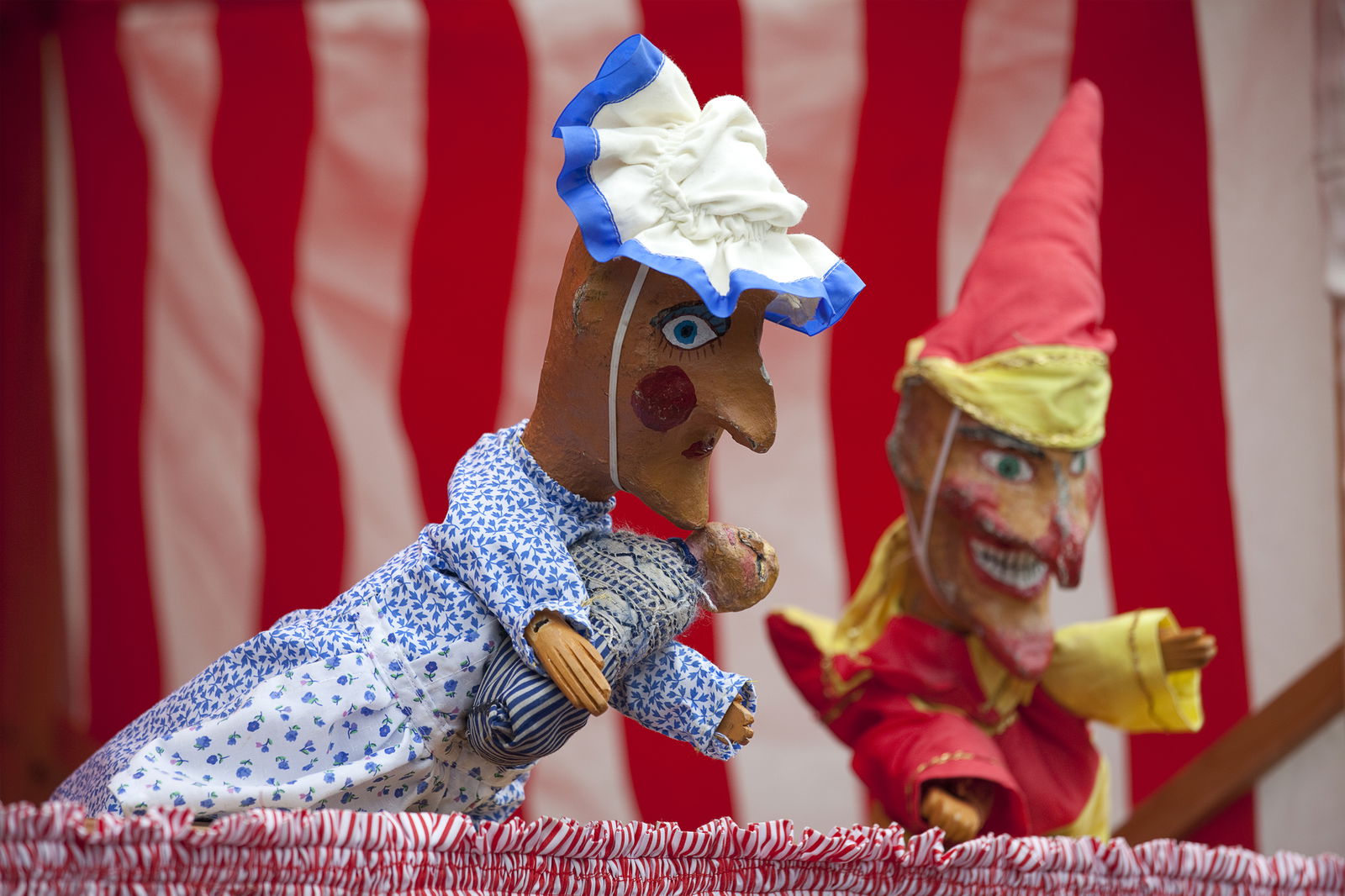 Zwei Handpuppen schauen über eine Kante aus dem Bild.