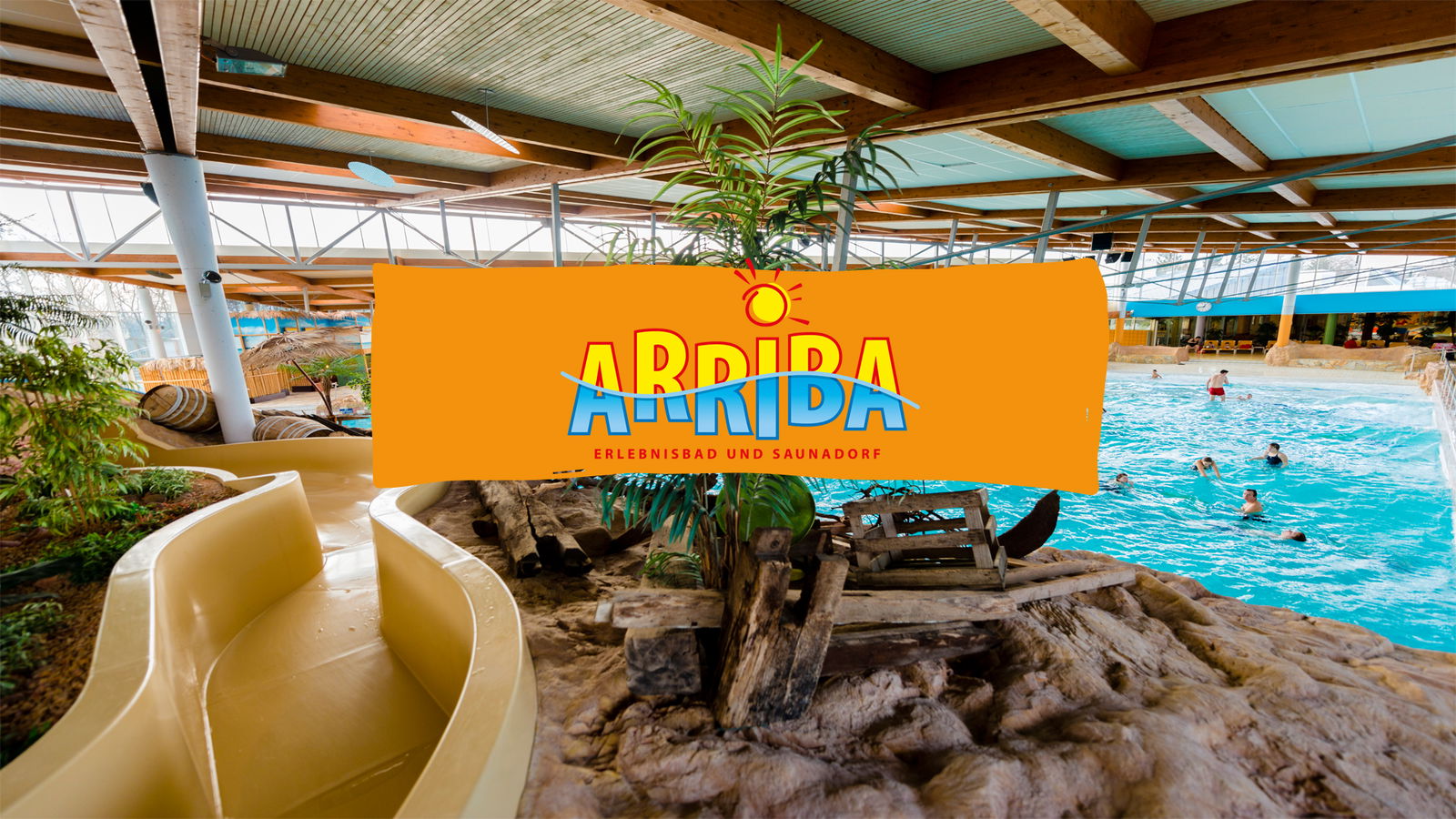 Das Erlebnisbad ARRIBA mit Palmen und einer gelben Rutsche sowie Badegästen. Vor dem Bild befindet sich ein gelbes Banner mit dem Logo des Erlebnisbades.