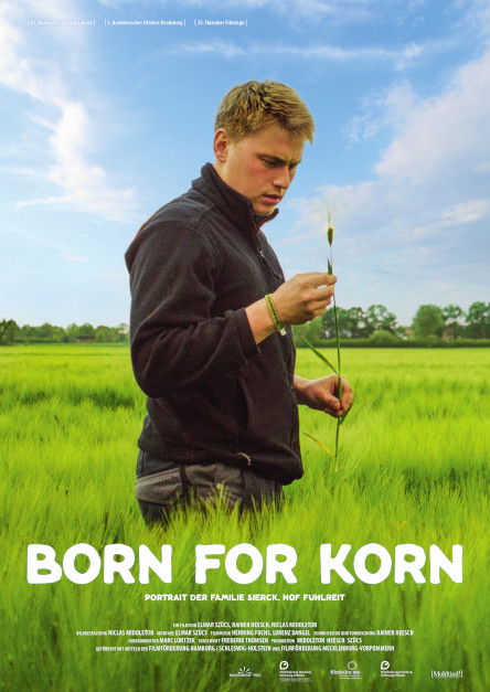 Ein Mann mit blonden Haaren steht in einem grünen Kornfeld.
