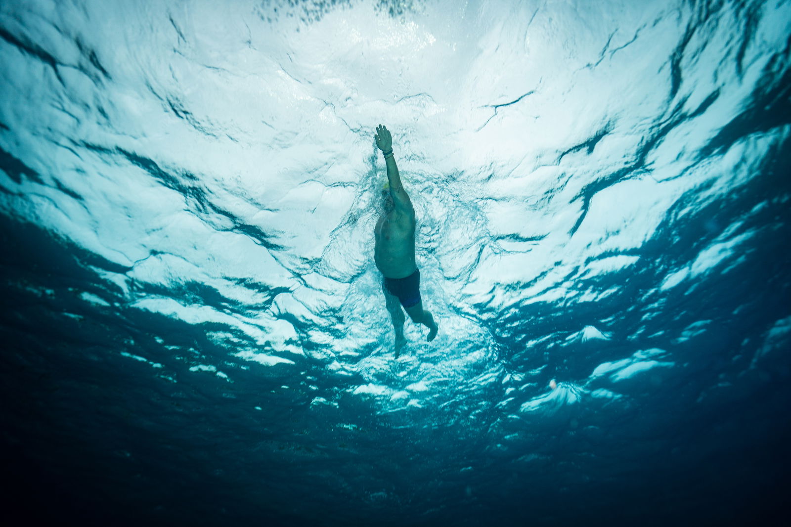 Ein Mann schwimmt in Untersicht im offenen Wasser