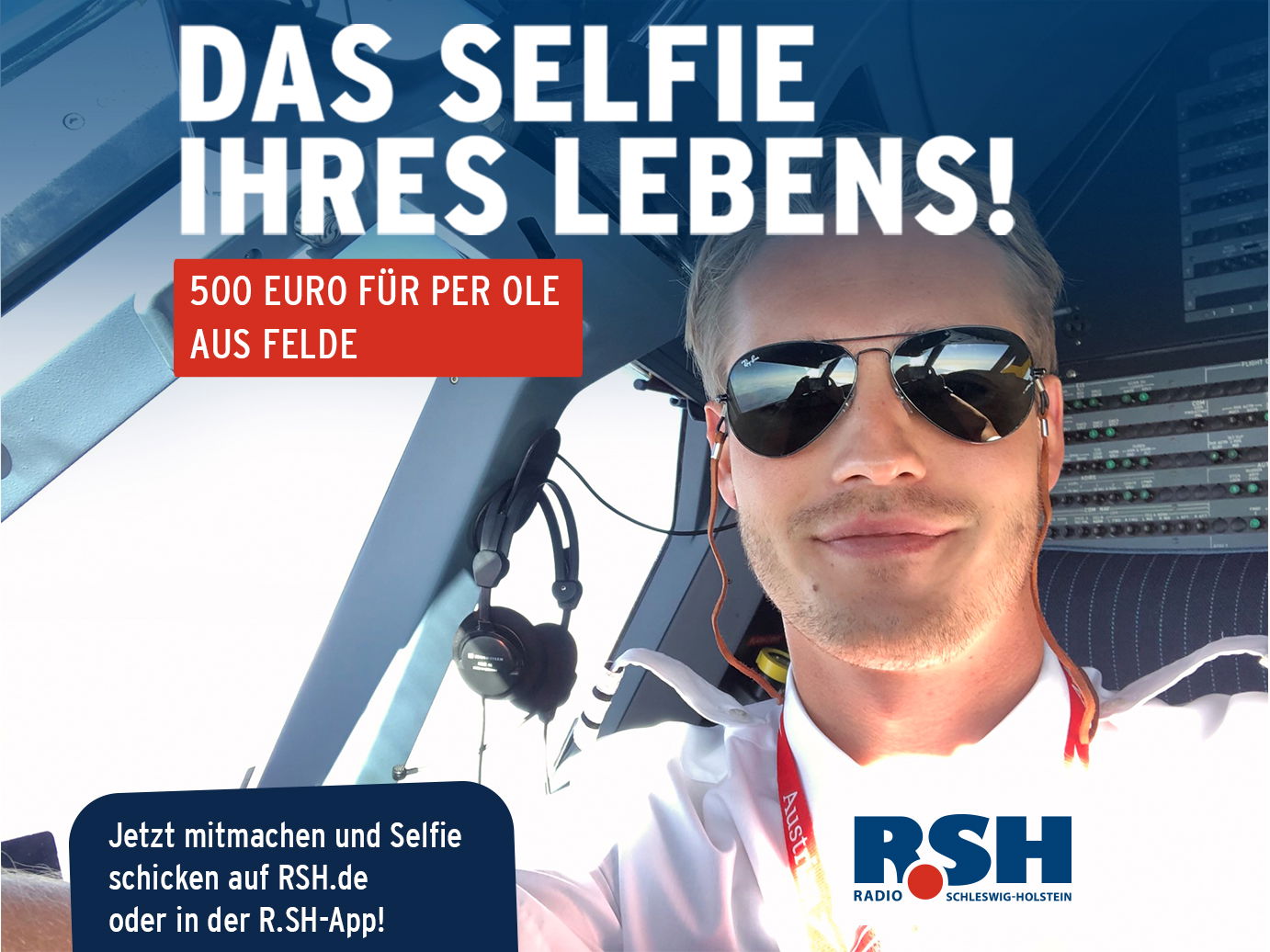 Ein junger Mann sitzt mit Pilotenuniform und Sonnenbrille im Cockpit eines Flugzeuges und macht ein Selfie von sich.