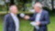 Carsten Kock steht mit R.SH-Mikrofon auf einer Wiese. Neben ihm steht im Anzug der SPD-Vorsitzende Norbert Walter-Borjans.