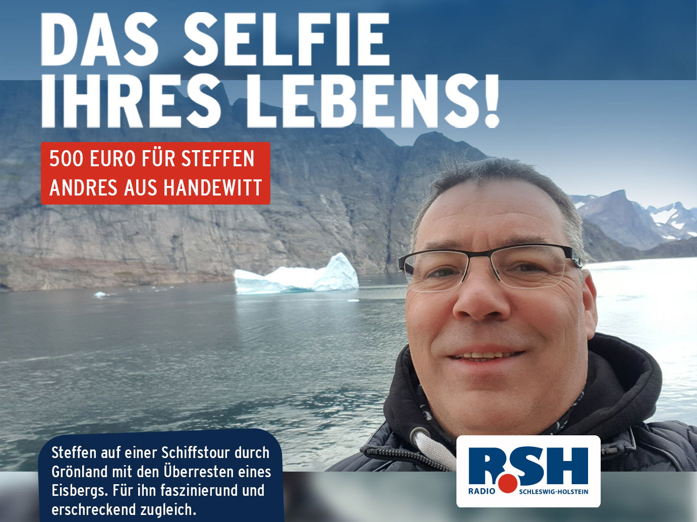 Ein Mann mit Brille auf See mit einem kleinen Eisberg im Hintergrund