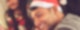 Ein junger Mann mit Weihnachtsmütze sitzt lächelnd an einem Tisch, auf dem ein verpacktes Geschenk liegt.