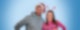 Matze Schmak und Ulrike Kirchner stehen weihnachtlich gekleidet und mit Weihnachtsmütze und Zuckerstangen auf dem Kopf vor hellblauem Hintergrund und lachen in die Kamera.