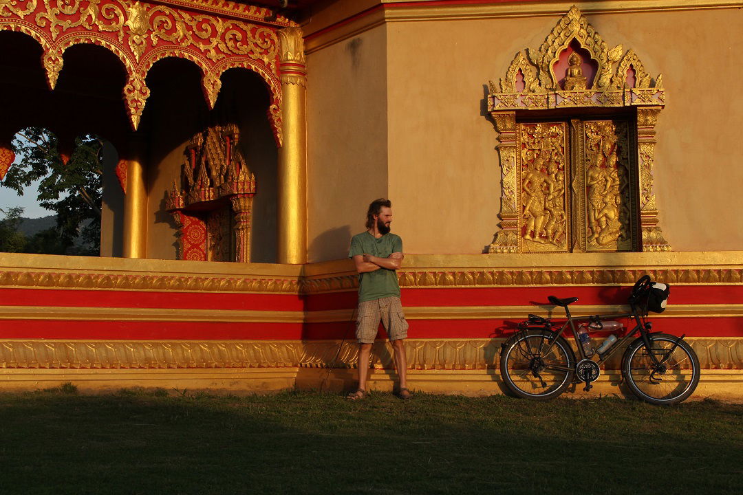Ein Mann mit seinem Fahrrad vor einem goldenen Palast im Sonnenuntergang