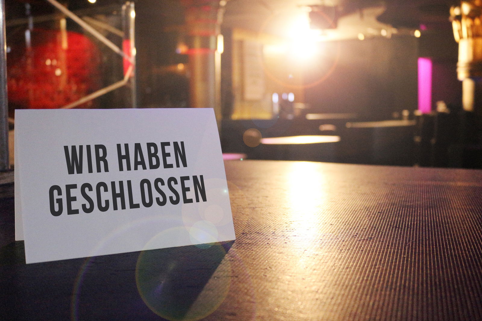 In einem dunklen Club steht ein Schild auf einem der Bartische