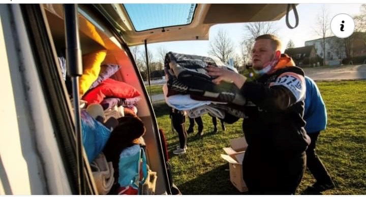 Ein Mann lädt Decken in den vollen Kofferraum eines Vans.