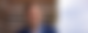 Thomas Losse-Müller steht an eine Holzwand gelehnt vor einer Wiese und lächelt in die Kamera.