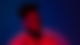 Kelvin Jones steht beleuchtet von einem roten Licht vor dunklem Hintergrund und schaut zur Seite.