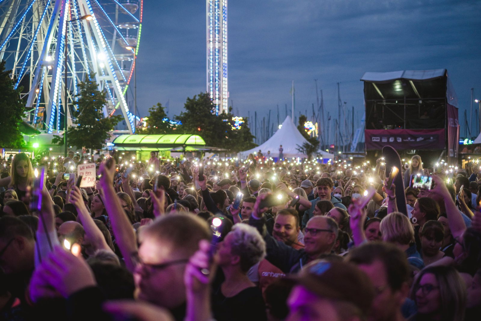 Singende Menschen vor einem Riesenrad.