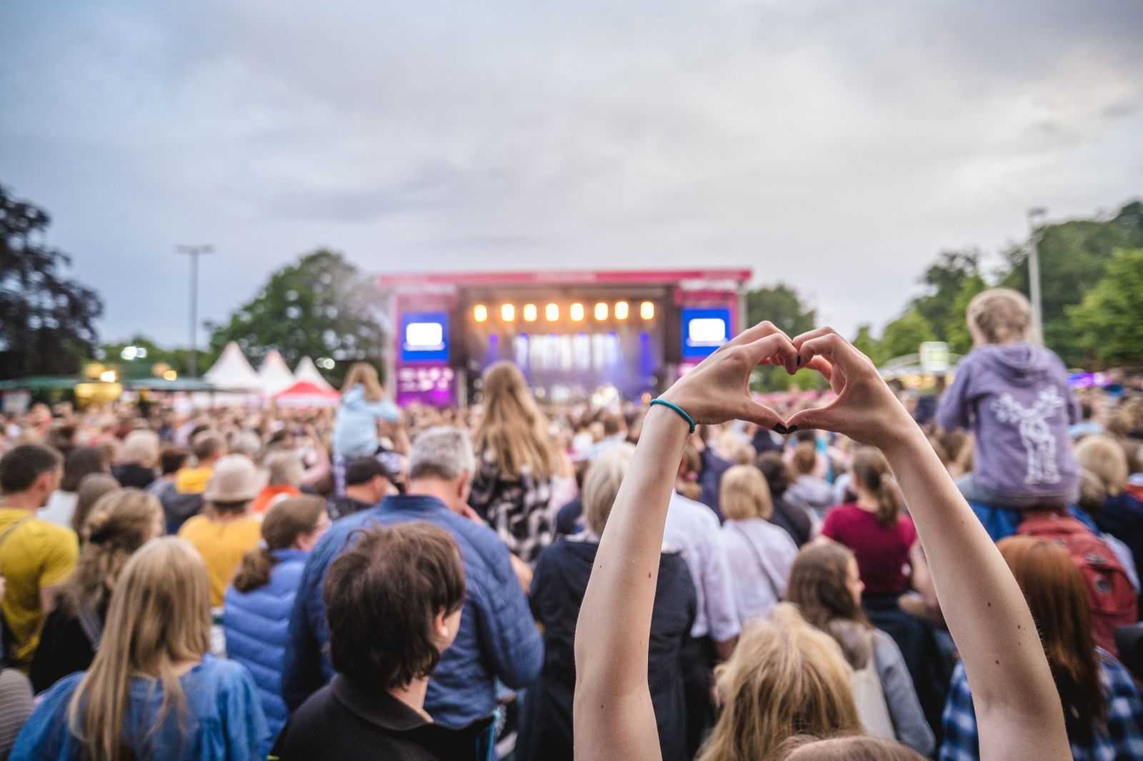 Eine Person formt mit den Händen ein Herz - im Hintergrund die R.SH-Bühne.