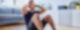 Ein sportlich-bekleideter Mann sitzt auf einer Sportmatte und macht Sit-Ups