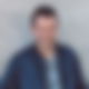 Dominik Feist steht vor einem grauen Hintergrund und lächelt in die Kamera.