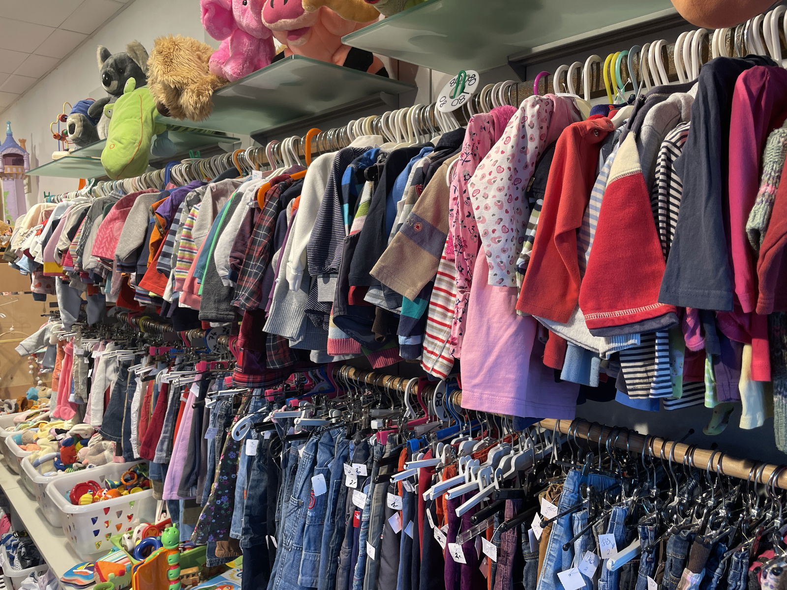 Kinderkleidung hängt an einem Ständer an der Wand