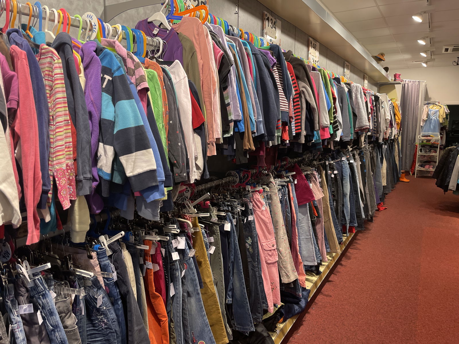 Kinderkleidung hängt an einem Ständer an der Wand