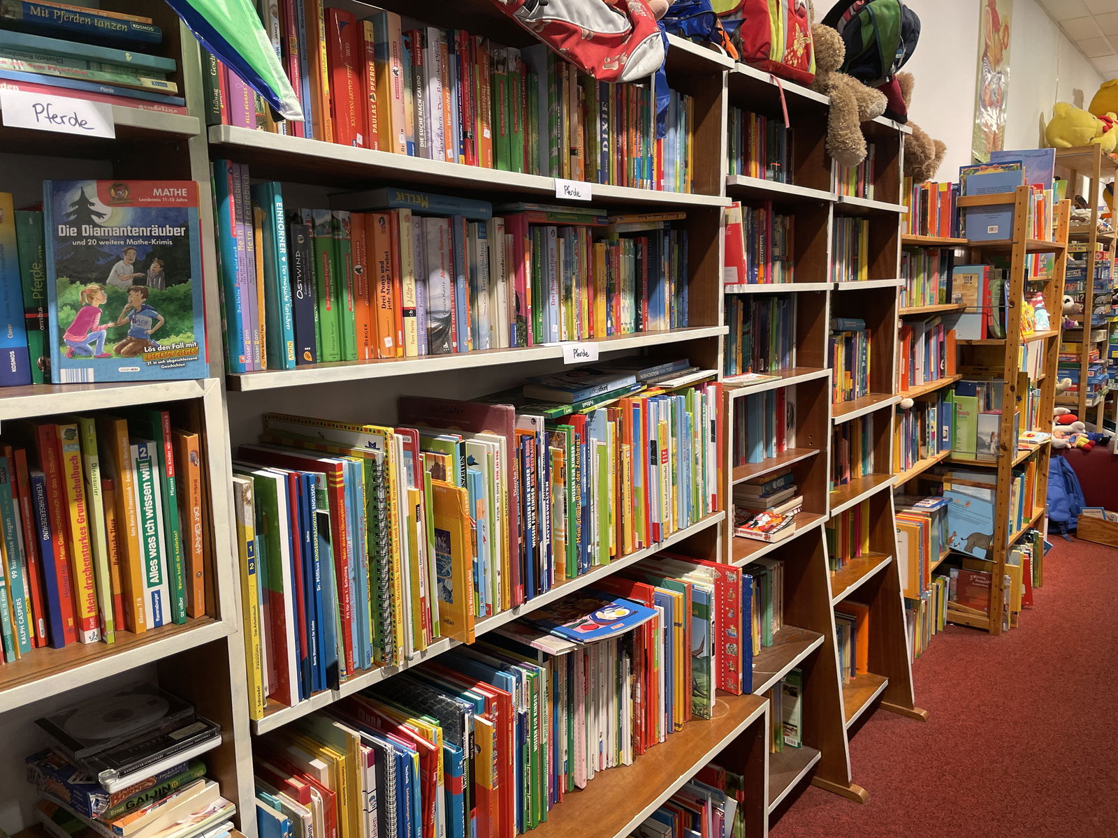 Viele Kinderbücher stehen in mehreren Regalen an der Wand