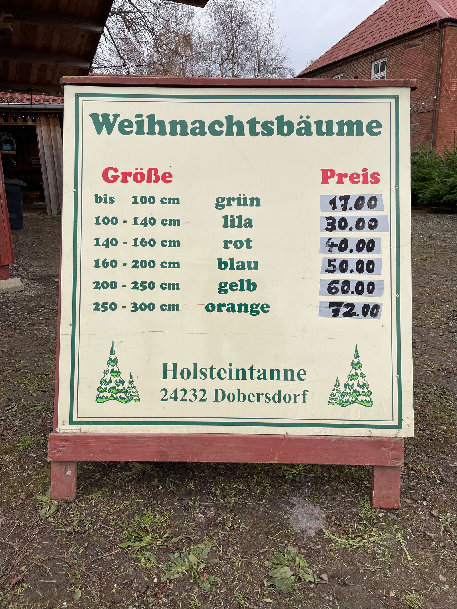 Auf einem Schild stehen Preise unter der Überschrift "Weihnachtsbäume".